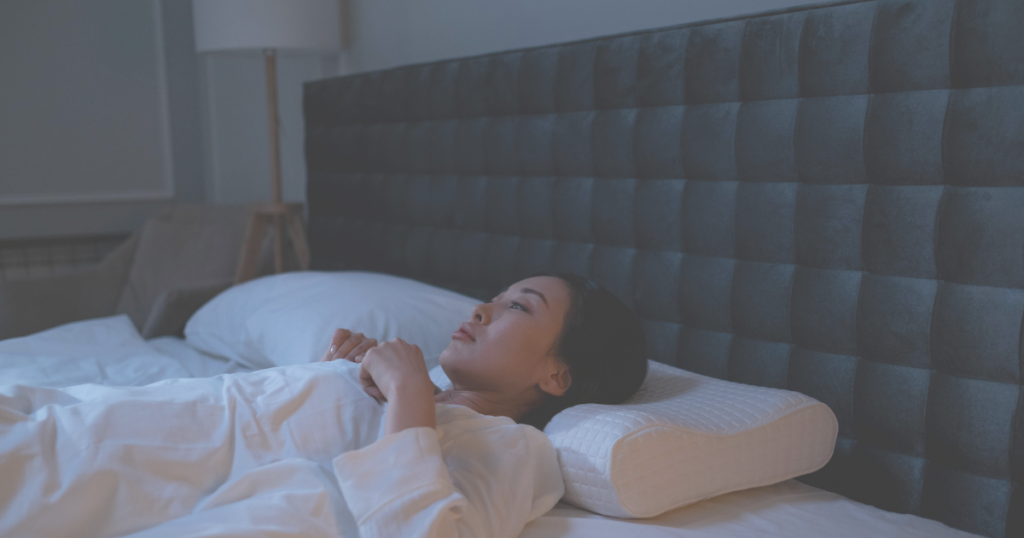 ベッドの中で眠れずにいる女性のイメージ図